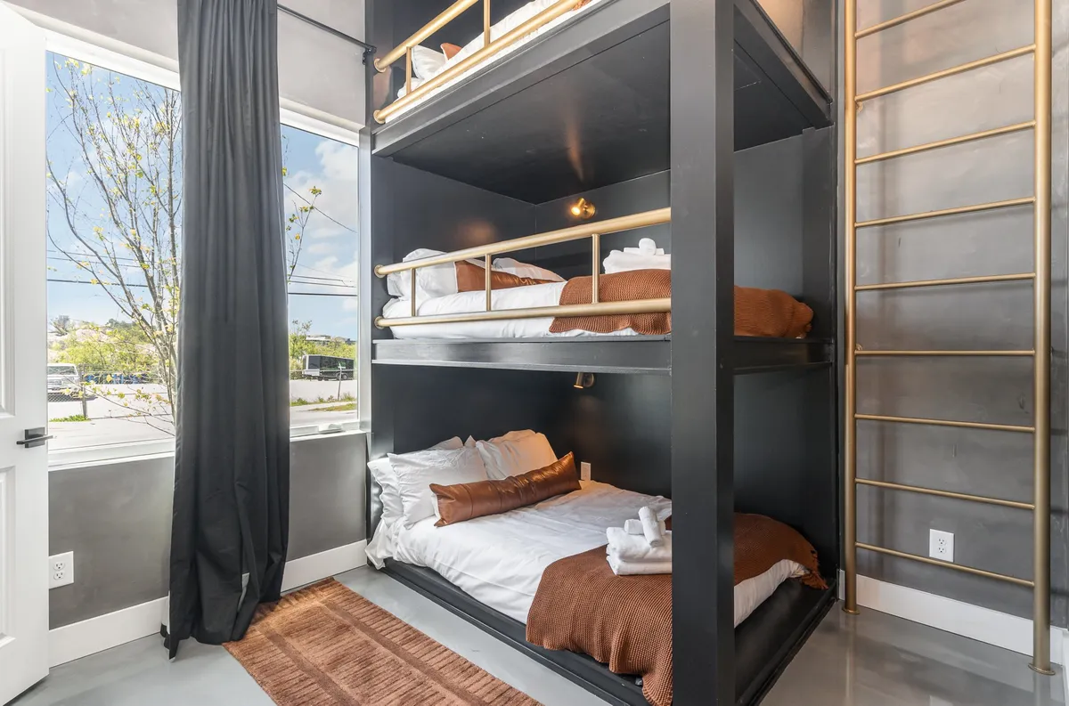 A dedicated bunk room with comfortable full-sized bunk beds, large window for natural light, and soft linens. The room exudes a playful yet restful mood, making it an ideal haven for kids or group members.